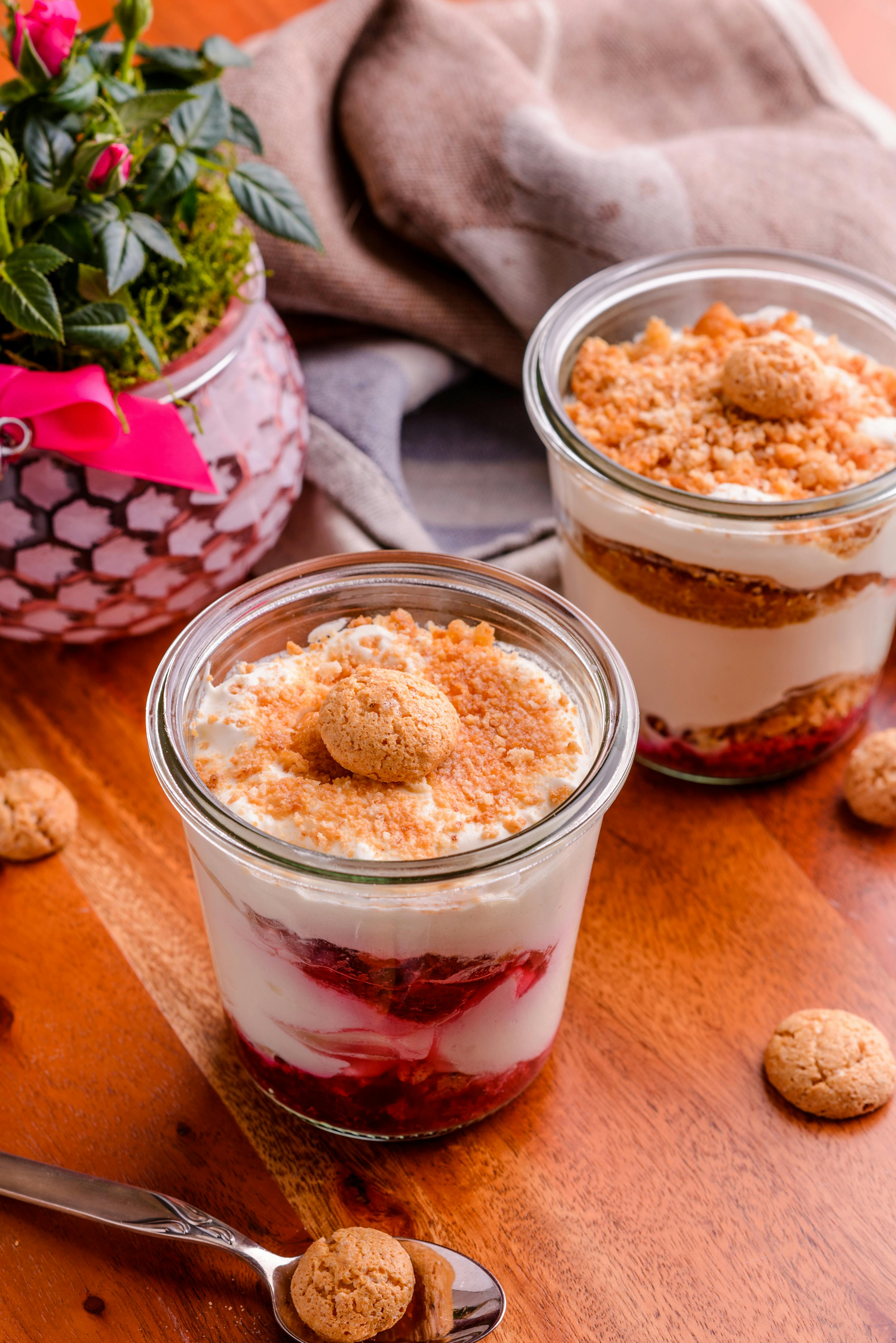 two amoretto affogato ice creams on a wooden table in small circular 
    glass serving containers with crushed biscuit on top